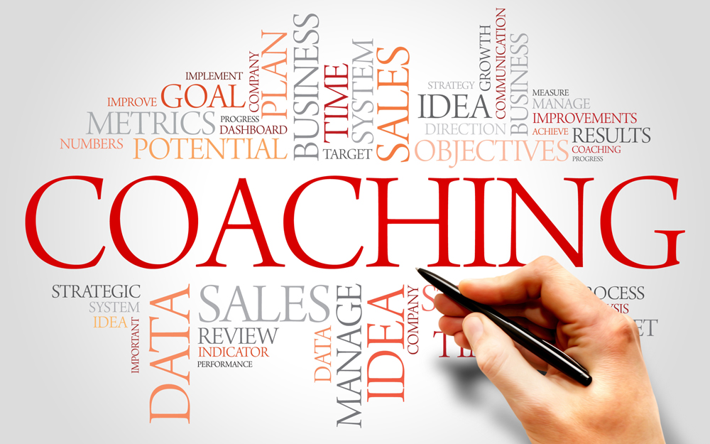 Hånd der skriver relevante ord der dækker ledelsescoaching